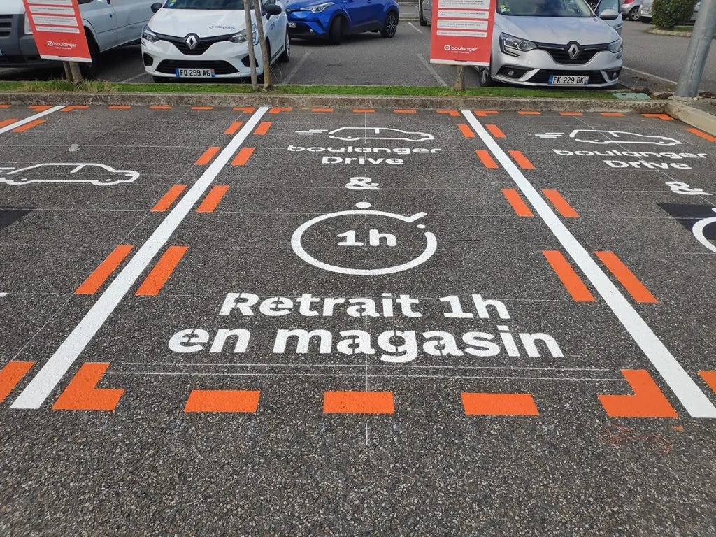 Emplacements Drive délimités par des lignes blanches et orange avec inscriptions de retrait en magasin