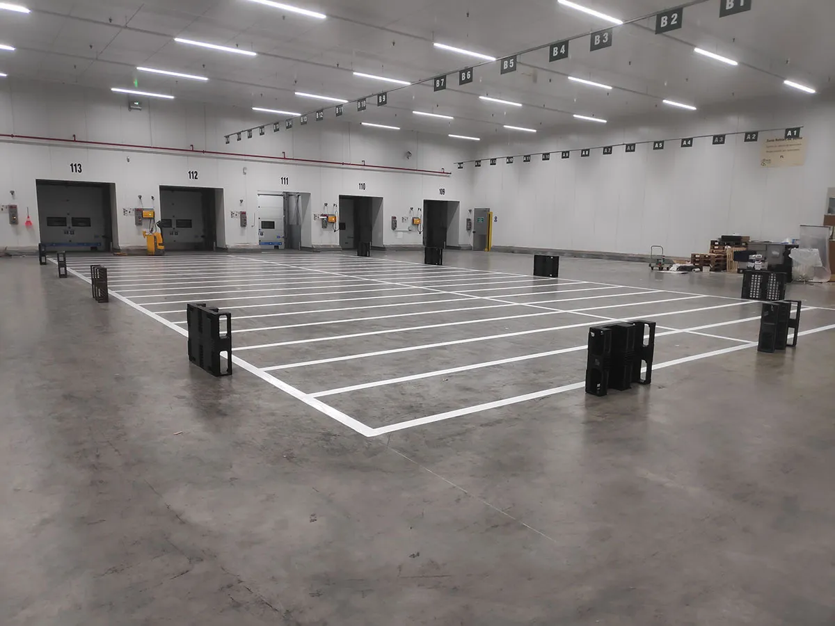 Emplacements logistiques délimités par des lignes blanches devant plusieurs quais intérieurs