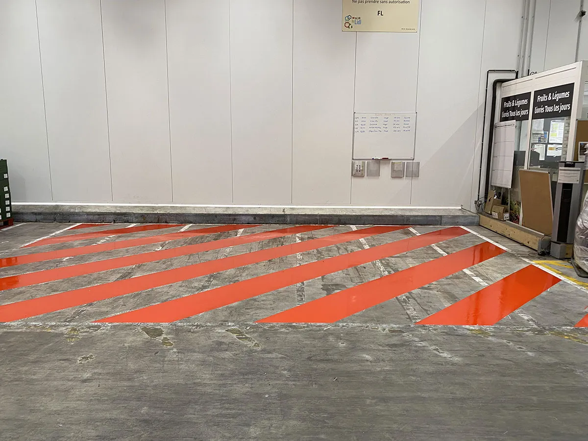 Larges bandes rouges peintes sur le sol d’une zone intérieure professionnelle