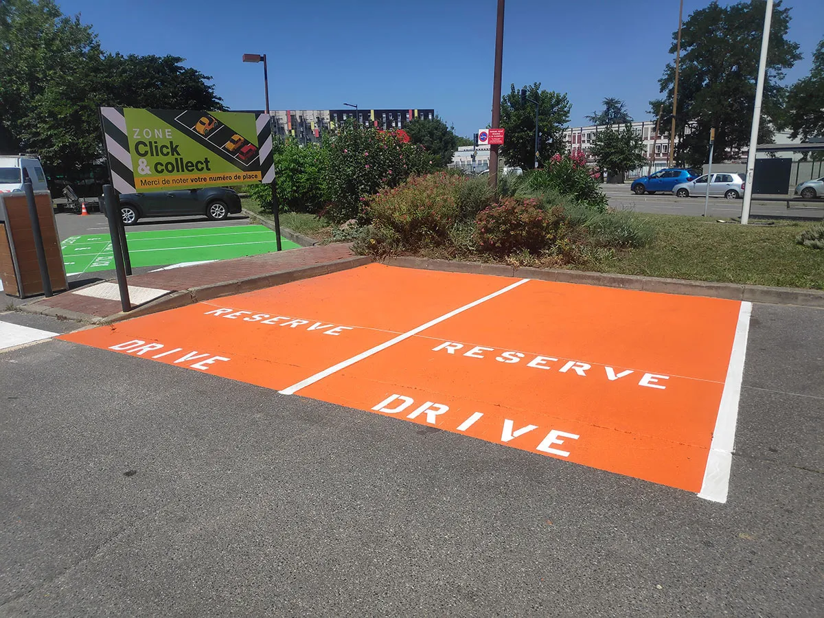 Deux places orange réservées au drive avec inscriptions blanches